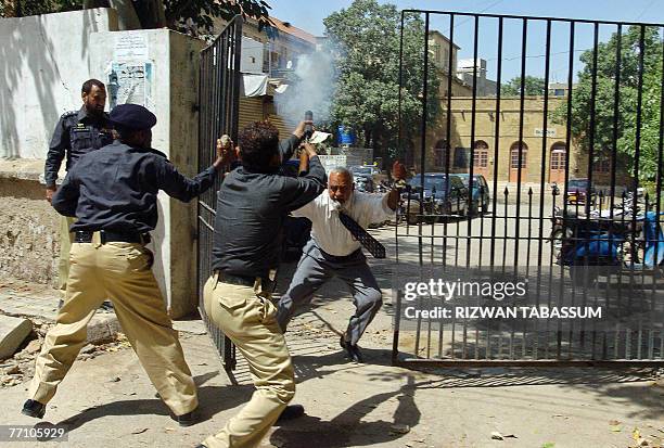 Pakistani policemen fire teargas shells in the city court area as a lawyer tries to close the gate during a protest in Karachi, 29 September 2007....