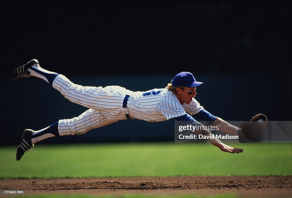 Baseball player diving to catch ball