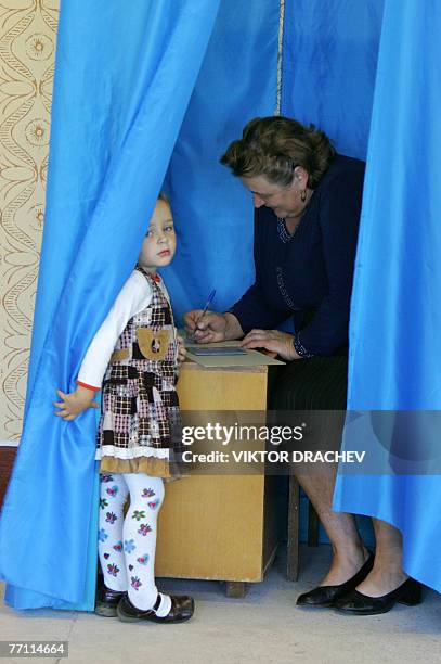 Girl looks out of the booth while her grandmother fills in ballot paper during the vote in the village of Dytiatky about 100 km from Kiev, 30...