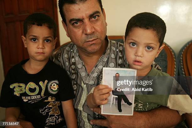 Palestinian boy Mohamad Hasan Al-Amodi, 2 1/2, holds a picture of his father Ayman Hasan Al-Amodi who has spent one year and nine months of two-year...