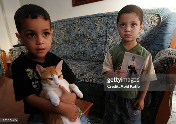 Palestinian boy Mohamad Hasan Al-Amodi, 2 1/2, holds a picture of his father Ayman Hasan Al-Amodi who has spent one year and nine months of two-year...