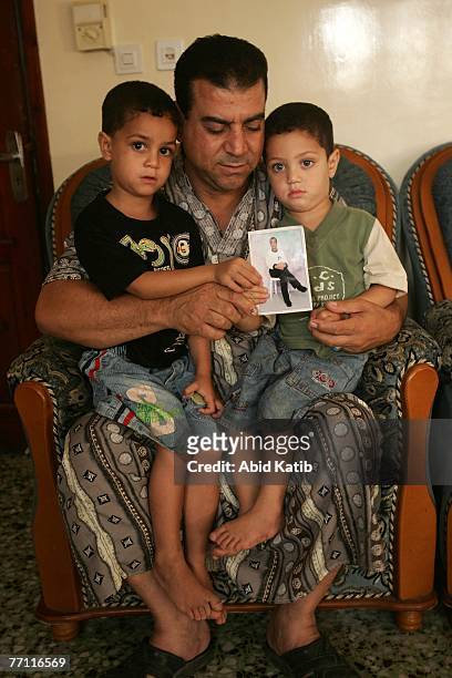 Palestinian boy Mohamad Hasan Al-Amodi, 2 1/2, holds a picture of his father Ayman Hasan Al-Amodi who has spent one year and nine months of two-year...