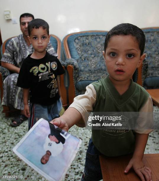 Palestinian boy Mohamad Hasan Al-Amodi, 2 1/2, holds a picture of his father Ayman Hasan Al-Amodi who has spent one year and nine months of two-year...