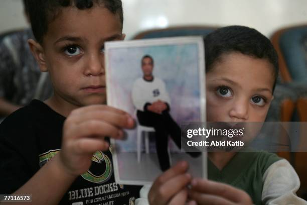 Palestinian boy Mohamad Hasan Al-Amodi, 2 1/2, and his brother Wade'a, 3 1/2, hold a picture of their father Ayman Hasan Al-Amodi who has spent one...