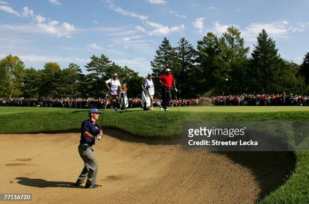 Mike Weir of Canada and the International Team hits a shot from the sand on the fifth hole as Tiger Woods of the U.S. Team looks on during the final...