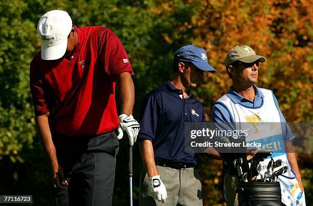 Mike Weir of canada and the International Team and his caddie Brennan Little look on as Tiger Woods of the U.S. Team reacts after a stray tee shot on...