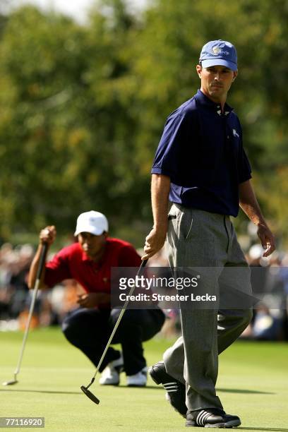 Mike Weir of the International Team looks over a putt as Tiger Woods of the U.S. Team looks on during the final day singles matches at The Presidents...