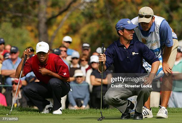 Mike Weir and his caddie Brennan Little of the International Team look over a putt as Tiger Woods of the U.S. Team looks on during the final day...