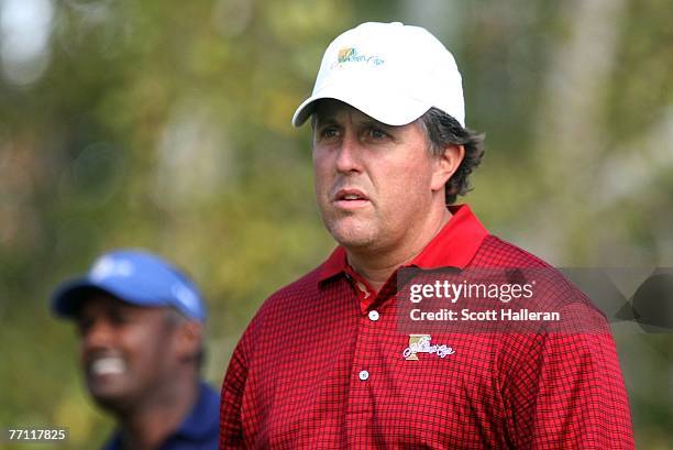 Phil Mickelson of the U.S. Team walks off the fourth tee as Vijay Singh looks on during the final day singles matches at The Presidents Cup at The...