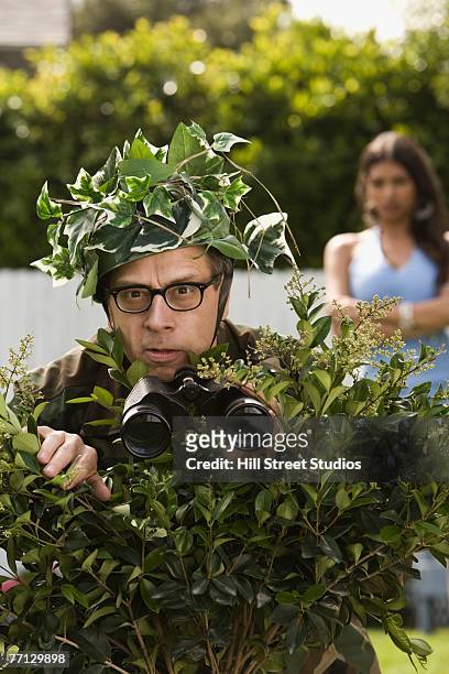 man using bush as camouflage - bad neighbor foto e immagini stock