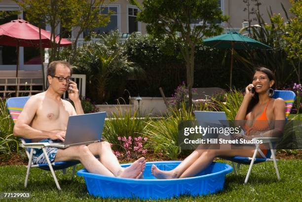 multi-ethnic couple with feet in kiddie pool - hot wet men ストックフォトと画像