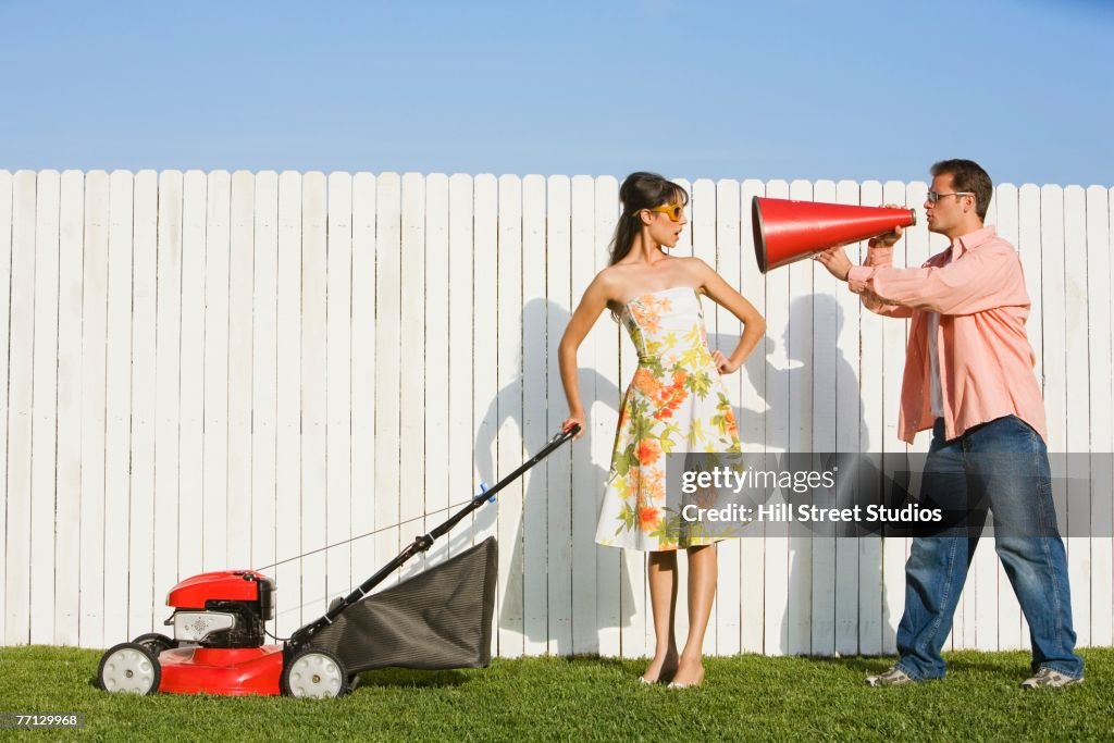 Man yelling at wife pushing lawn mower