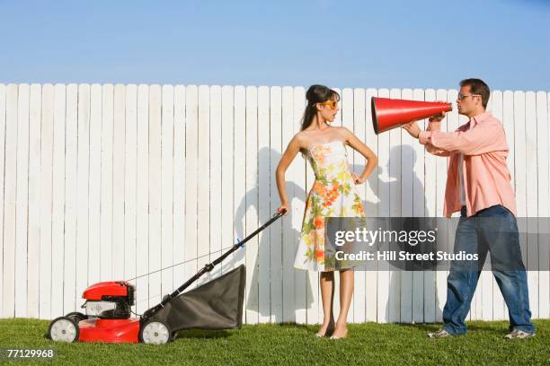man yelling at wife pushing lawn mower - tegendraads stockfoto's en -beelden