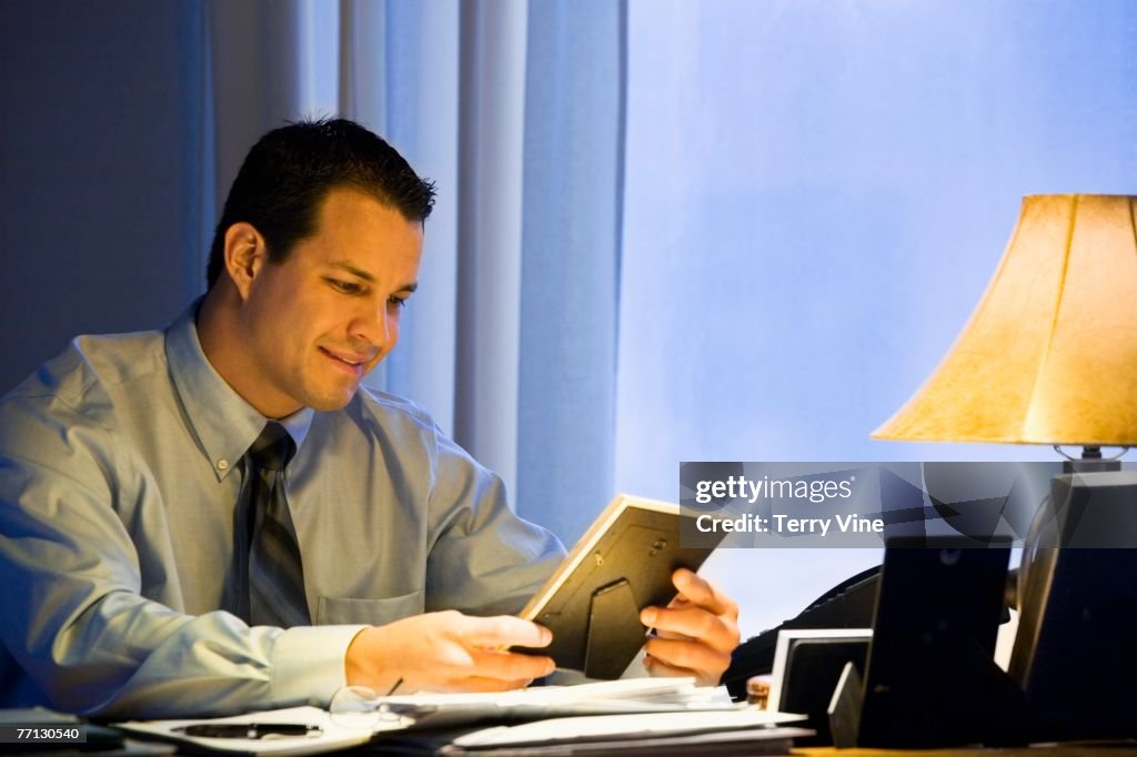 Hispanic businessman looking at framed photograph