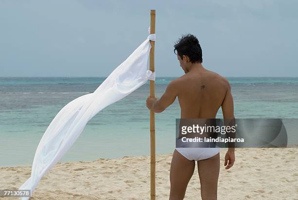 hispanic man holding flag at beach - the castaway ストックフォトと画像