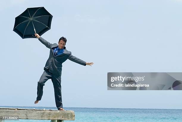 hispanic businessman holding umbrella on dock - hesitant to dance stock pictures, royalty-free photos & images