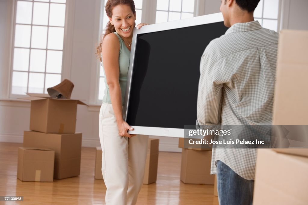 Hispanic couple carrying television