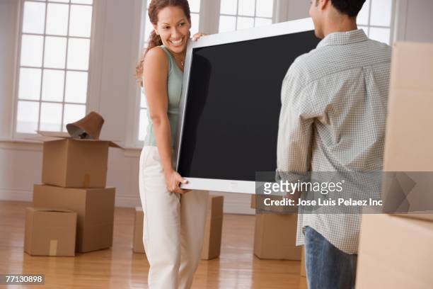 hispanic couple carrying television - carrying tv stock pictures, royalty-free photos & images