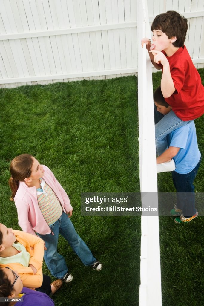 Mixed Race boys looking over fence at girls