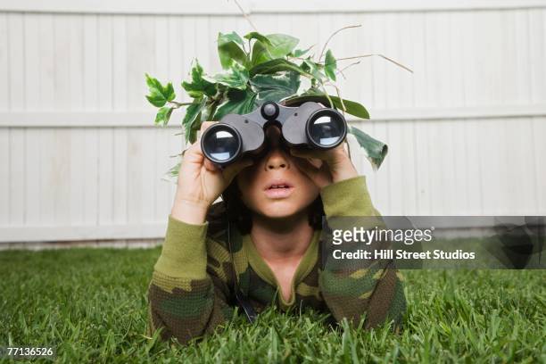 mixed race boy looking through binoculars - kamouflagekläder bildbanksfoton och bilder