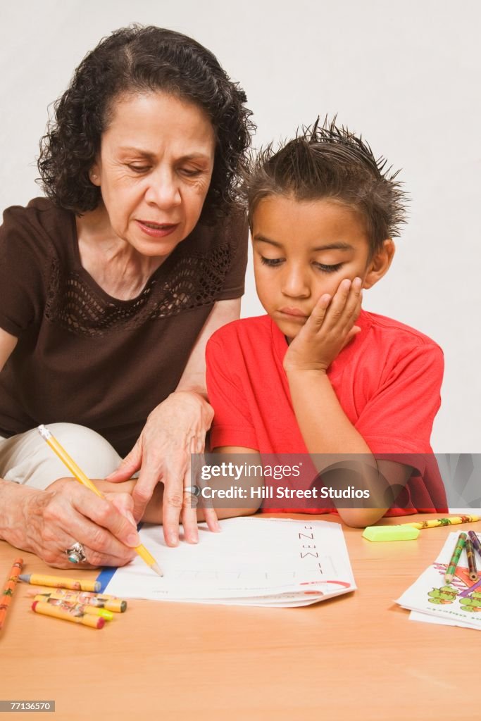 Hispanic grandmother helping grandson with homework
