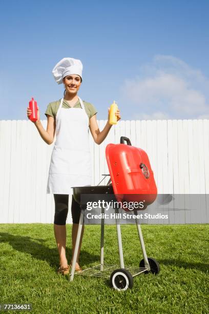 hispanic woman barbecuing - tablier photos et images de collection