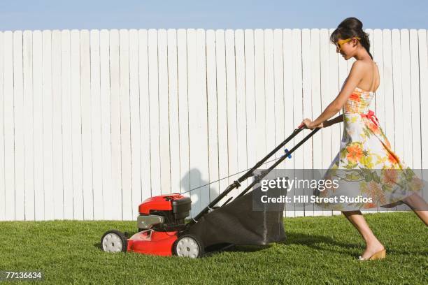 hispanic woman in dress pushing lawn mower - grasmaaier stockfoto's en -beelden