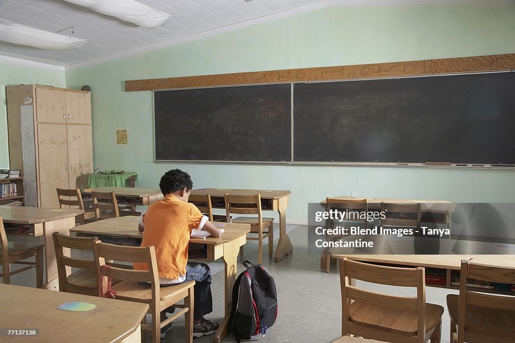 Mixed Race boy in empty classroom