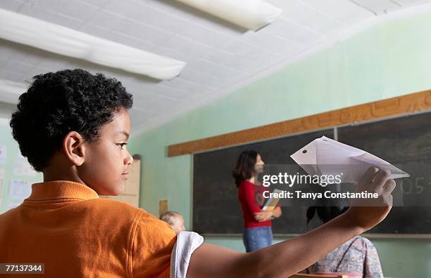 mixed race boy throwing paper airplane in class - naughty in class stock pictures, royalty-free photos & images