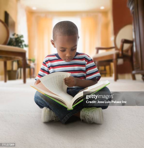 african american boy reading on floor - boy sitting on floor stockfoto's en -beelden