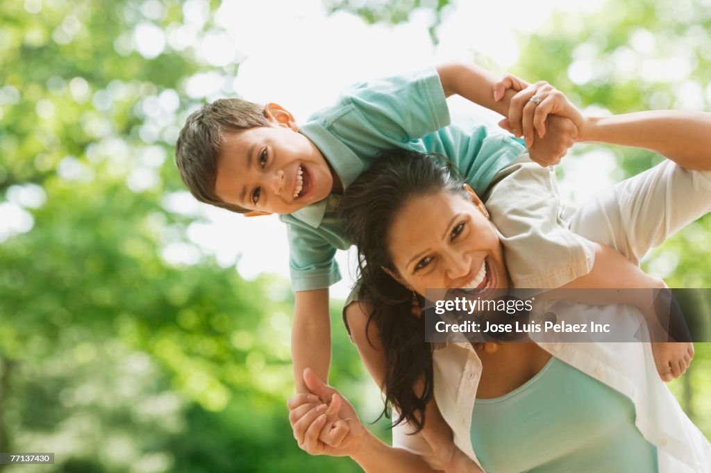 Hispanic mother holding son on shoulders