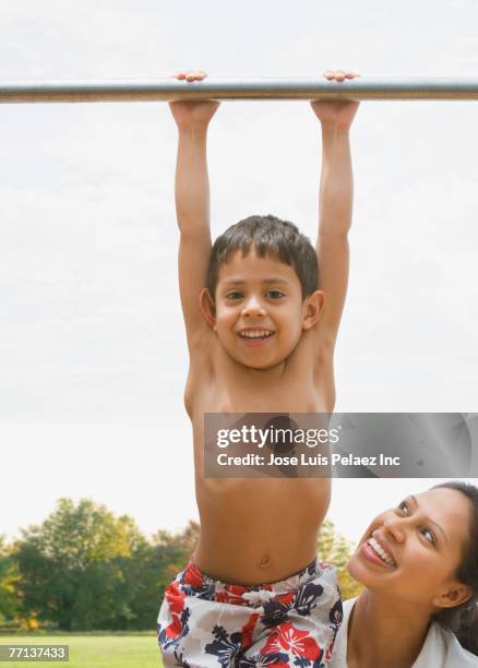 hispanic boy hanging from bar - boys in pullups stock-fotos und bilder