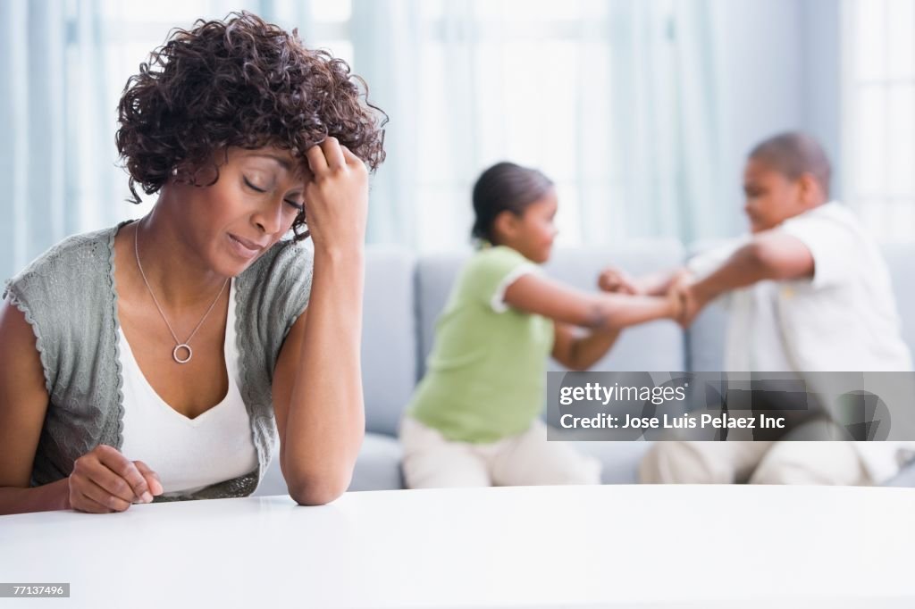 Frustrated African American mother with children fighting