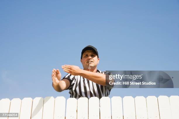 hispanic referee making call over fence - foul sports - fotografias e filmes do acervo