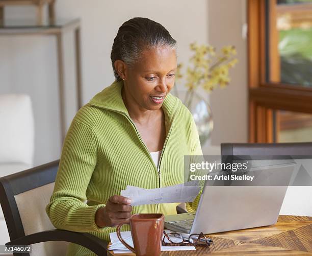 senior african american woman paying bills - stolen identity stock pictures, royalty-free photos & images