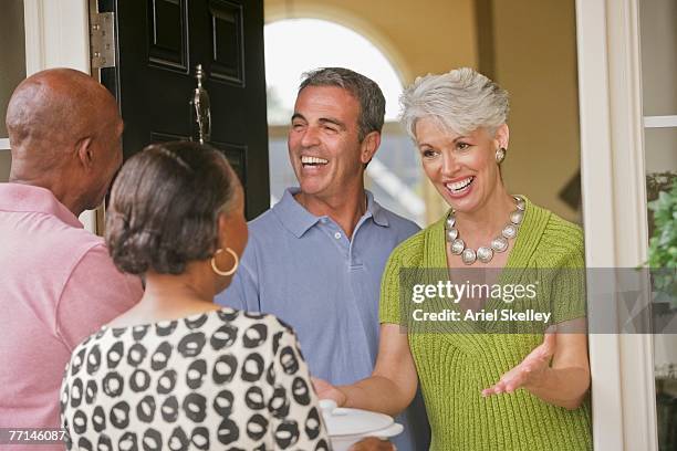 multi-ethnic senior couples greeting in doorway - welcoming guests fotografías e imágenes de stock