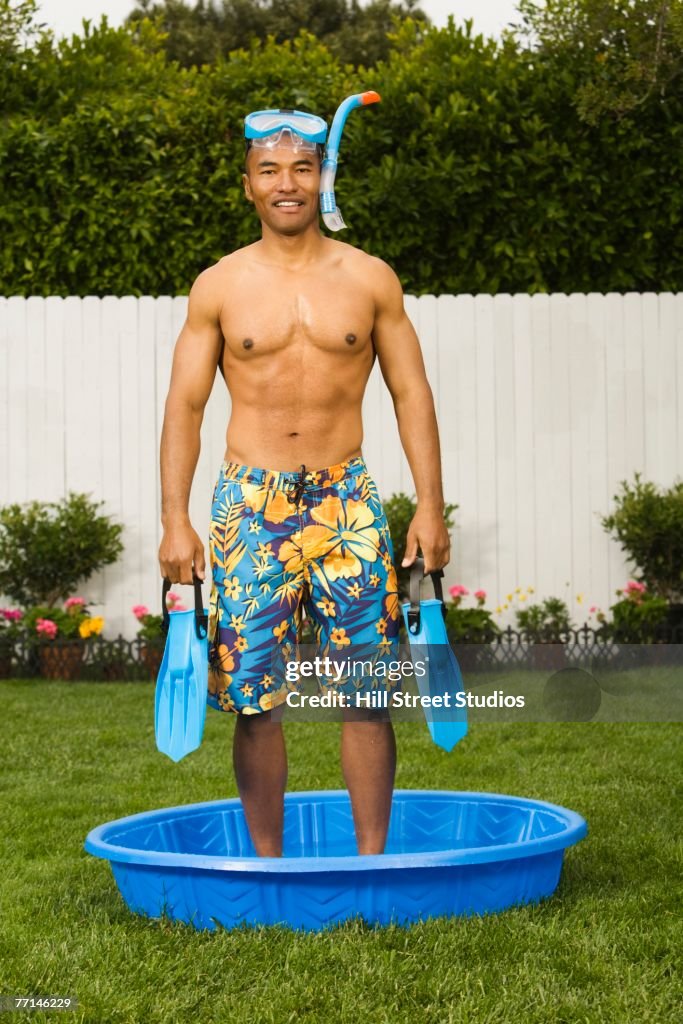 Mixed Race man standing in kiddie pool
