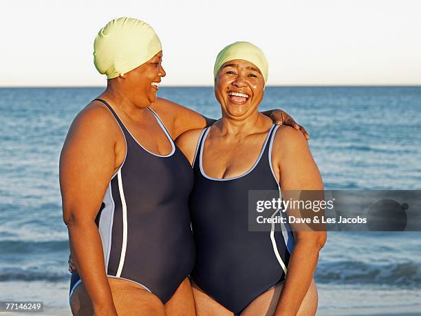 mixed race women in swimming caps on beach - frau lachen profil stock-fotos und bilder