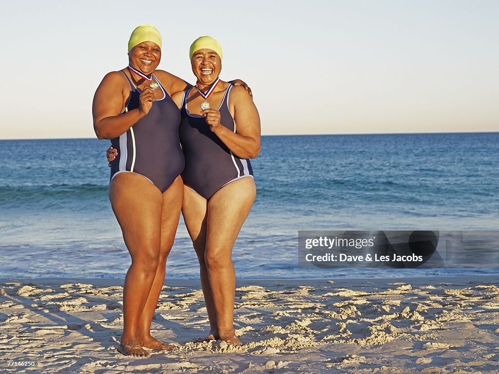 Mixed Race women with medals on beach