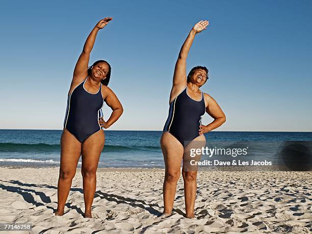 mixed race women stretching at beach - african woman swimming stock pictures, royalty-free photos & images