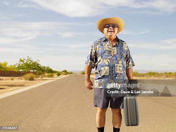 senior mixed race man holding suitcase - hawaiihemd stock-fotos und bilder