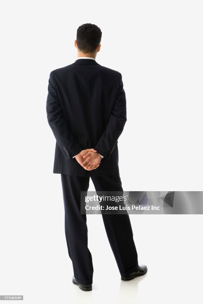 Hispanic businessman with hands behind back