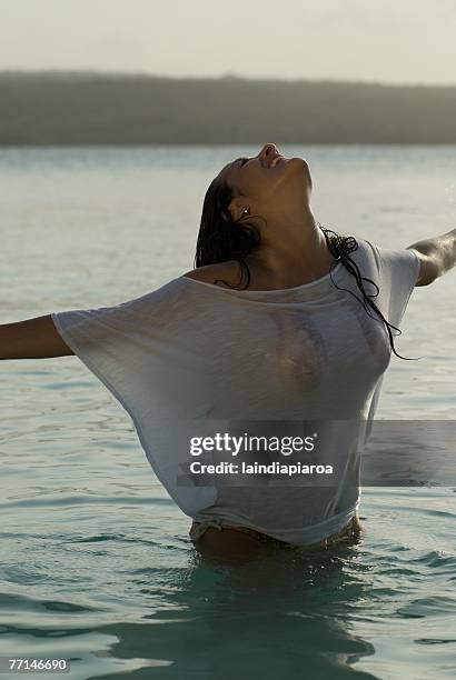 hispanic woman wearing shirt in water - women in wet tee shirts stock pictures, royalty-free photos & images