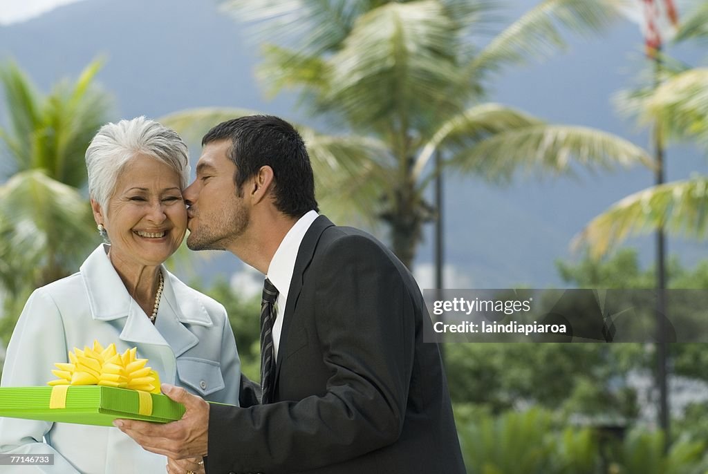 Hispanic man giving gift to mother