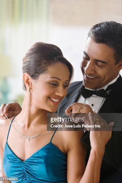 hispanic man putting diamond necklace on wife - diamond necklace stock pictures, royalty-free photos & images