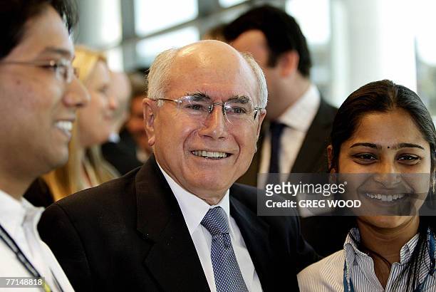 Australian Prime Minister John Howard poses for a photograph as he mingles with staff during his tour of the new Optus national headquarters near...