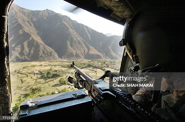 Solder holds a machine gun as he sits onboard a Chinook helicopter while flying over the Panjshir province, some 100 kilometers north of Kabul, 02...