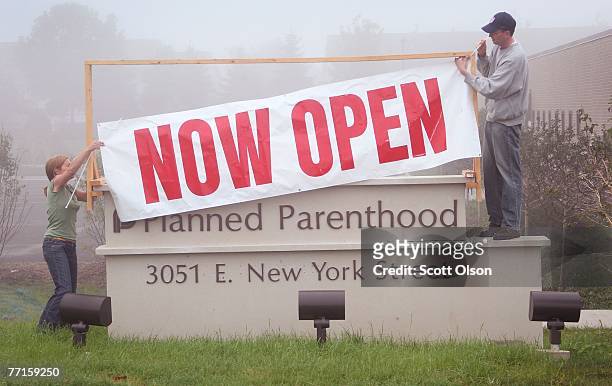 Workers at a Planned Parenthood clinic hang a banner to announce the opening of the facility October 2, 2007 in Aurora, Illinois. The clinic,...