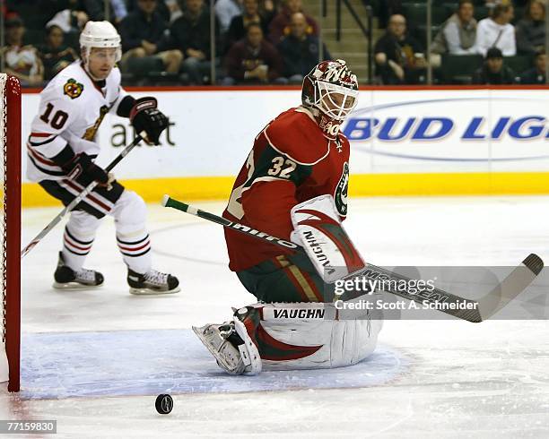 Niklas Backstrom of the Minnesota Wild makes a save as Patrick Sharp of the Chicago Blackhawks looks for a rebound in a preseason game September 30,...