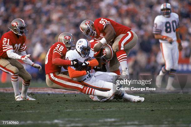 Linebacker Keena Turner and defensive tackle Michael Carter of the San Francisco 49ers tackle Miami Dolphins wide receiver Nat Moore during Super...